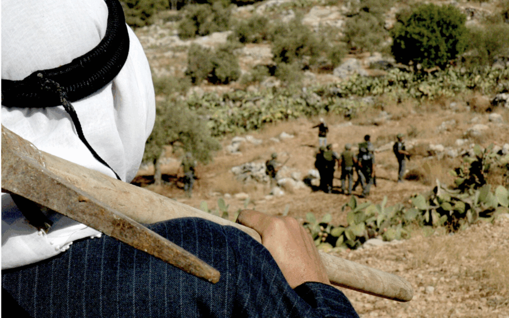 Contadino palestinese osserva soldati israeliani nei campi di ulivi a Budrus.
