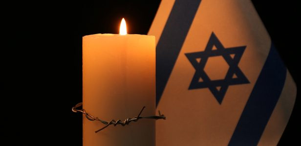 Candela accesa accanto alla bandiera di Israele in memoria delle vittime della Shoah.