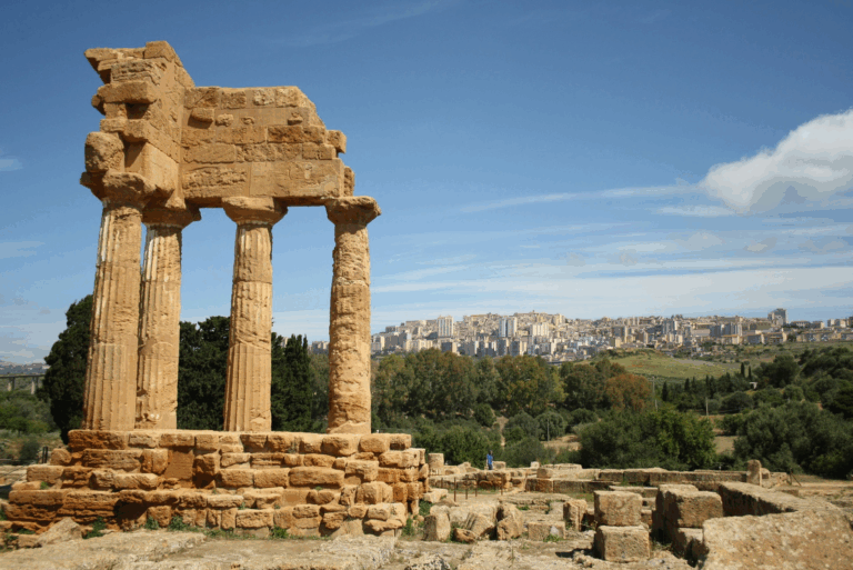 Rovine del Tempio dei Dioscuri nella Valle dei Templi ad Agrigento, con vista sulla città sullo sfondo