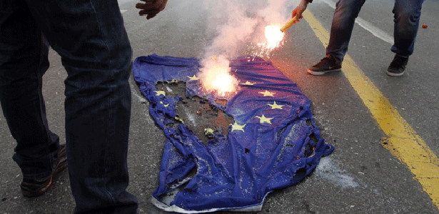 Bandiera dell'Unione Europea bruciata a terra durante una manifestazione di protesta.