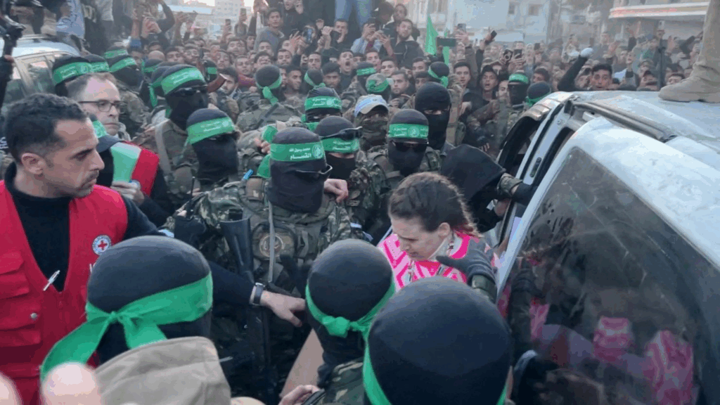 Ostaggi israeliani circondati da miliziani di Hamas durante una fase di rilascio a Gaza, tra folla e tensione.