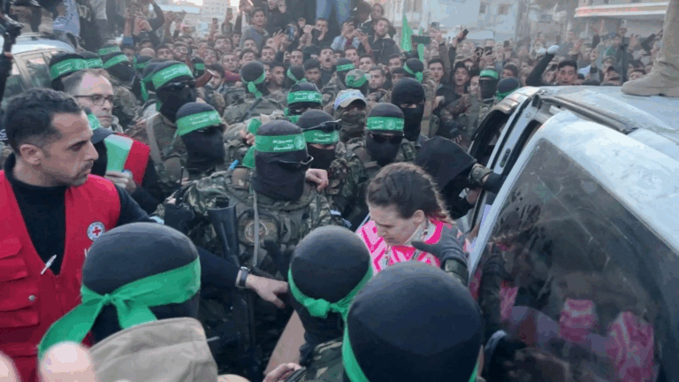 Ostaggi israeliani circondati da miliziani di Hamas durante una fase di rilascio a Gaza, tra folla e tensione.