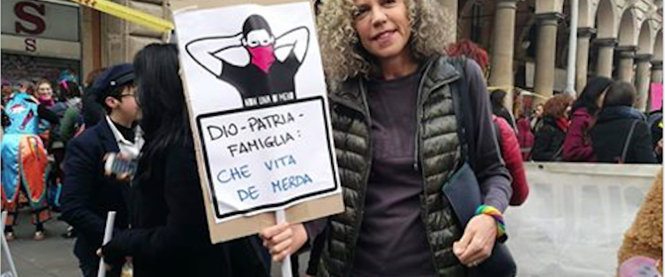 Donna a una manifestazione tiene un cartello con la scritta ironica "Dio, patria, famiglia? Che vita di m***a", criticando lo slogan conservatore.