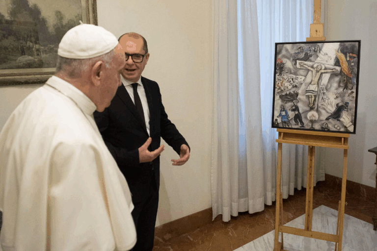 Papa Francesco osserva la "Crocifissione bianca" di Chagall durante un'esposizione, accompagnato da un curatore o storico dell’arte.