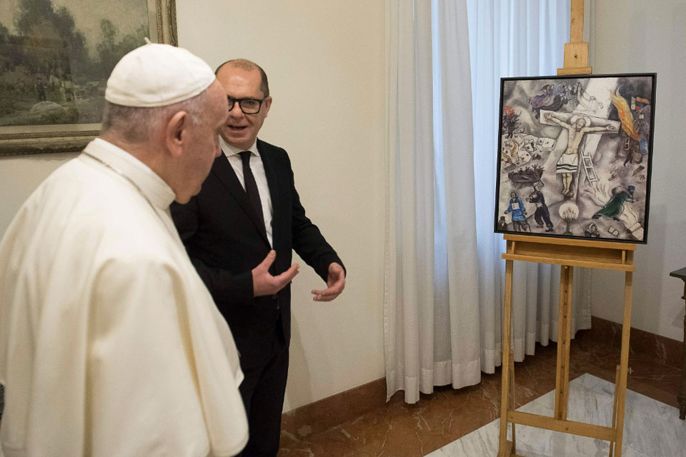 Papa Francesco osserva la "Crocifissione bianca" di Chagall durante un'esposizione, accompagnato da un curatore o storico dell’arte.