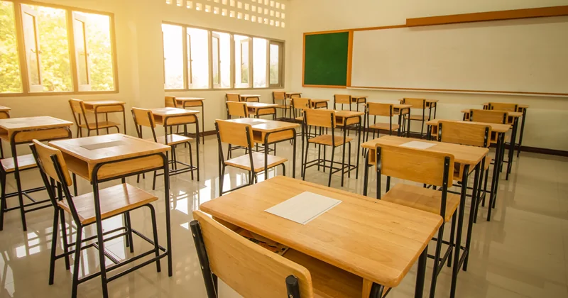 Aula scolastica vuota con banchi e sedie ordinati