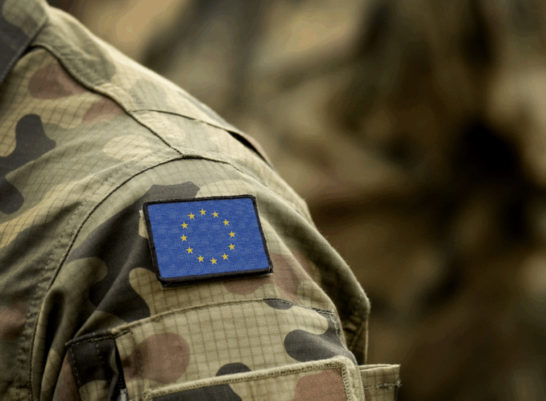 Soldato con uniforme mimetica e patch della bandiera dell’Unione Europea, simbolo della difesa comune e dell’autonomia strategica europea.