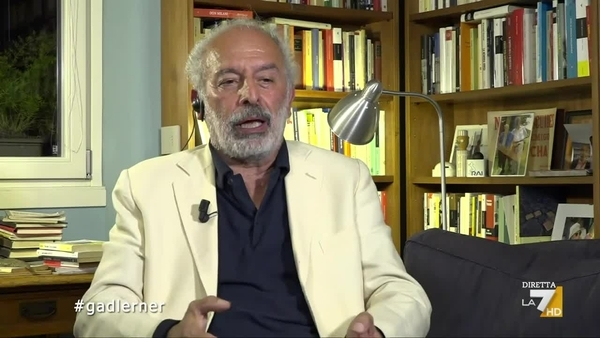 Gad Lerner in collegamento TV dallo studio di casa, libreria sullo sfondo, concetto intellettuale ebraicità politica in Italia