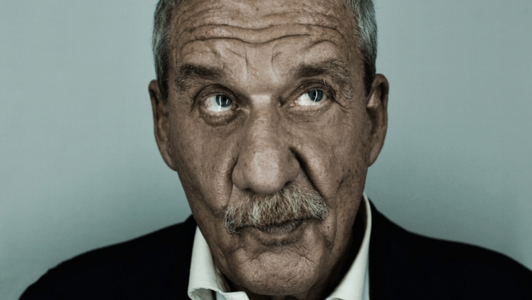 Primo piano di Paolo Conte, cantautore italiano iconico, espressione ironica e surreale, simbolo della musica d’autore.