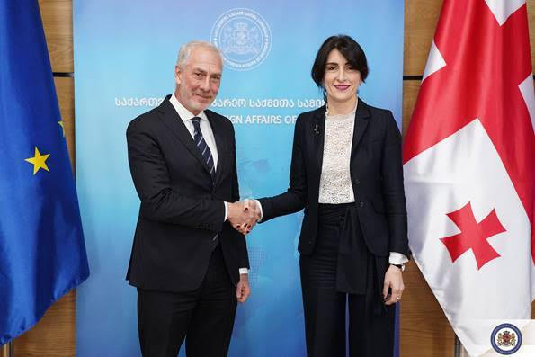 L’ambasciatore italiano Massimiliano D’Antuono stringe la mano alla ministra georgiana Maka Botchorishvili davanti alle bandiere dell’UE e della Georgia.