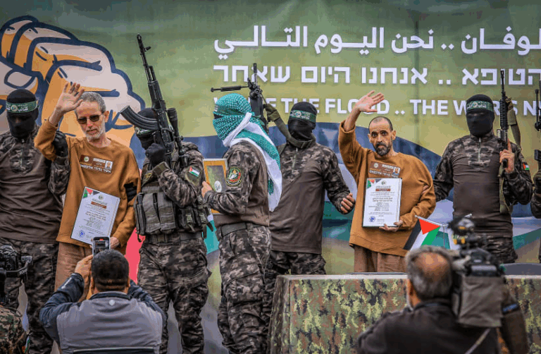 "Ostaggi israeliani rilasciati da Hamas, mostrati pubblicamente accanto a miliziani armati mascherati durante una messa in scena propagandistica."