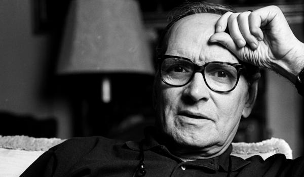 Ritratto in bianco e nero di Ennio Morricone, seduto con espressione riflessiva, simbolo del suo genio musicale