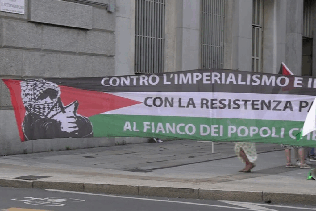 Striscione di protesta con bandiera palestinese e slogan contro l’imperialismo e a sostegno della resistenza popolare, esposto in una manifestazione.