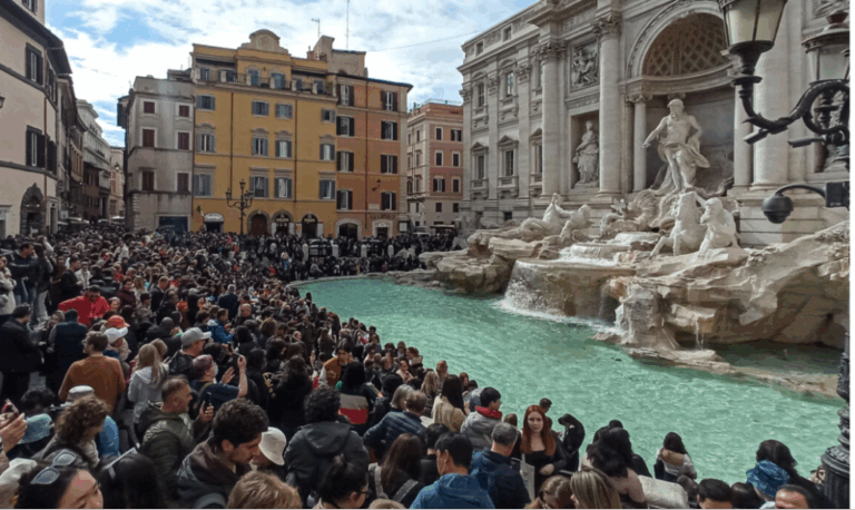 Folla di turisti davanti alla Fontana di Trevi a Roma, simbolo dell’overtourism nelle città d’arte.