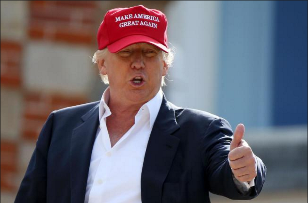 Donald Trump con cappellino rosso Make America Great Again durante evento pubblico, simbolo della narrativa trumpiana negli USA