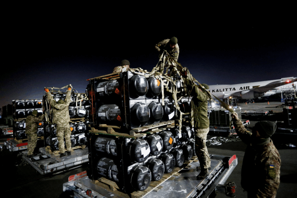 Soldati NATO caricano equipaggiamento militare in un aeroporto europeo per missione di supporto all’Ucraina contro l’invasione russa.