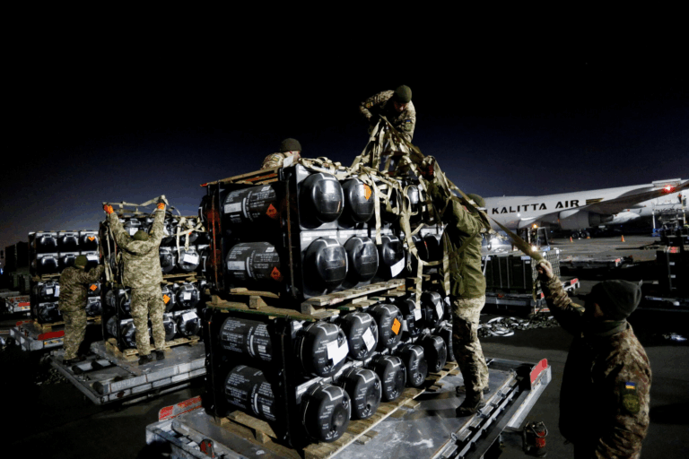 Soldati NATO caricano equipaggiamento militare in un aeroporto europeo per missione di supporto all’Ucraina contro l’invasione russa.