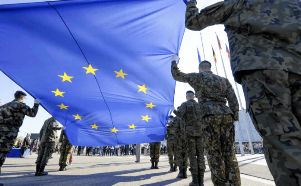 Militari europei sfilano con la bandiera dell’Unione Europea, simbolo del riarmo e della difesa comune europea