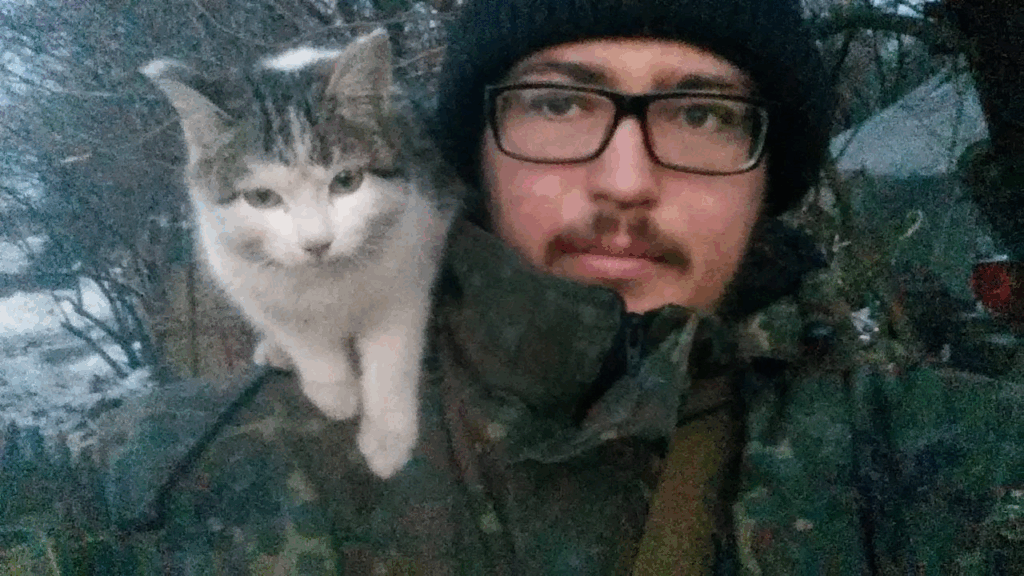 Nazar Rozlutsky, intellettuale ucraino al fronte, in mimetica con un gatto sulla spalla: resistenza e umanità in trincea.