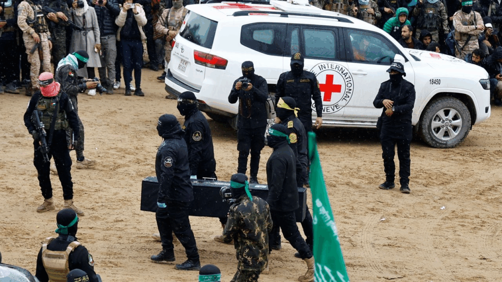 Miliziani di Hamas in parata con veicolo Croce Rossa sullo sfondo: simbolo delle ambiguità nel conflitto israelo-palestinese.