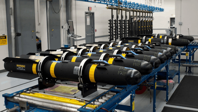 Linea di produzione industriale con missili o armamenti in fase di assemblaggio, all’interno di uno stabilimento militare ad alta tecnologia.