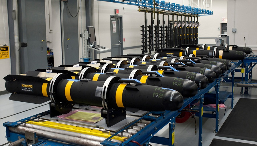 Linea di produzione industriale con missili o armamenti in fase di assemblaggio, all’interno di uno stabilimento militare ad alta tecnologia.