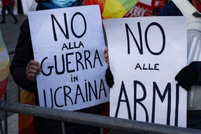 Manifestanti con cartelli “No alla guerra in Ucraina” e “No alle armi” durante protesta pacifista