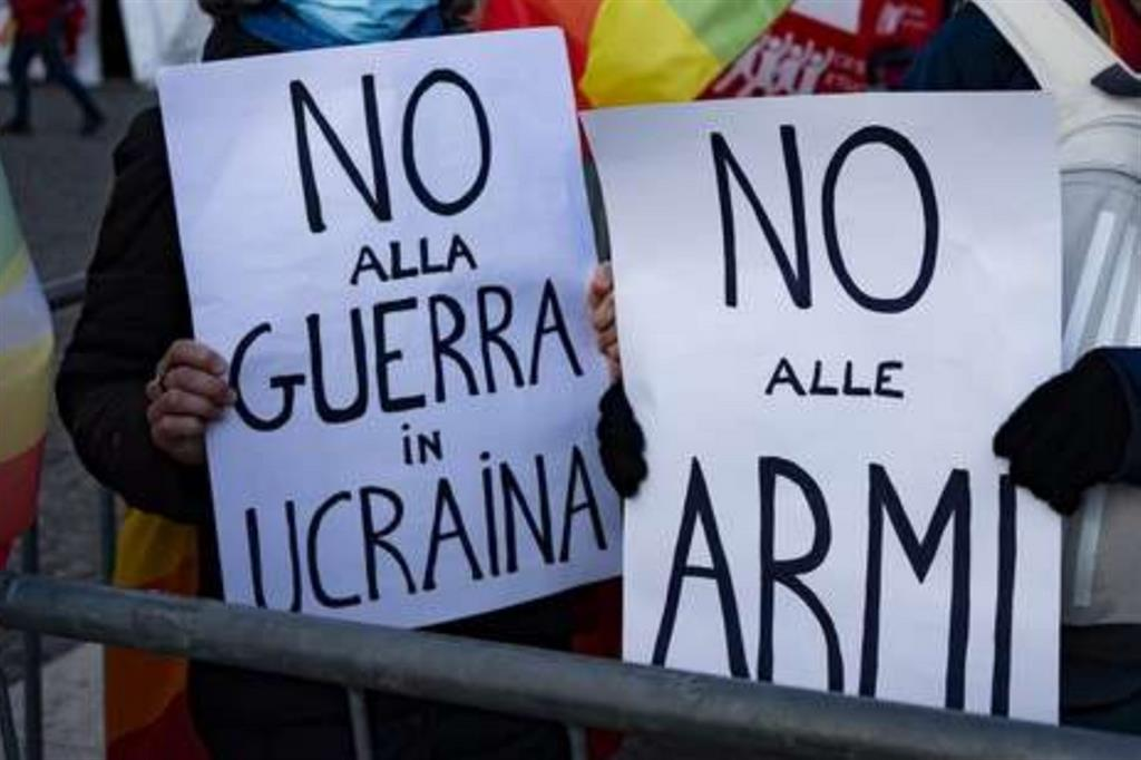 Manifestanti con cartelli “No alla guerra in Ucraina” e “No alle armi” durante protesta pacifista