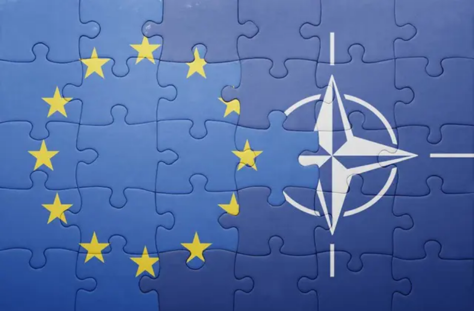 Bandiera dell'Unione Europea e logo NATO a puzzle: simbolo dell'integrazione strategica europea nella difesa atlantica