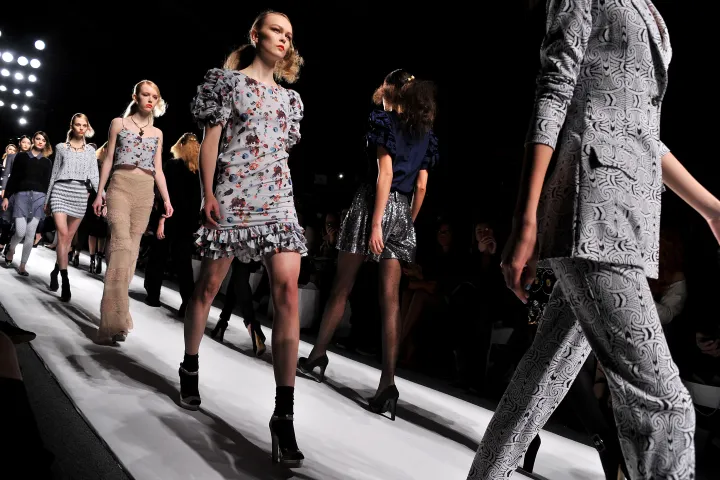 Sfilata di moda con modelle in passerella, simbolo della standardizzazione estetica promossa dai media contemporanei.