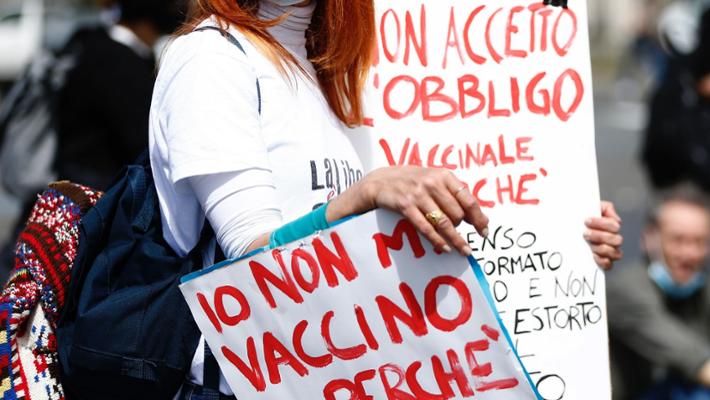 Dettaglio di una manifestazione con cartelli scritti a mano, espressione di disinformazione