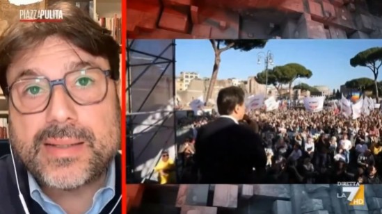 Intervento televisivo con Tomaso Montanari affiancato da un’immagine di manifestazione pubblica sulla difesa europea.