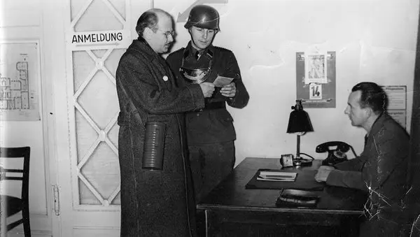 William L. Shirer, giornalista americano, interrogato da ufficiali militari durante la Seconda guerra mondiale in un ufficio d’epoca
