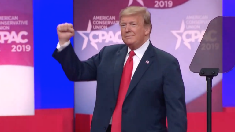 Donald Trump al CPAC 2019 mentre saluta il pubblico con il pugno alzato, sullo sfondo il logo della conferenza conservatrice